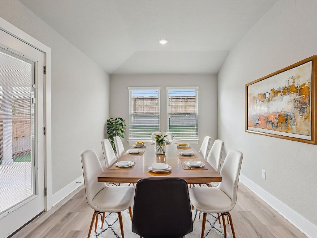 305 Gristmill Road Burnet, TX 78611 - Photo 8 of 21 Photo is not of the actual home, but is an inspirational photo of builder’s model home and may depict options, furnishings, and/or decorator features that are not includedDining room with light wood finished floors and lofted ceiling