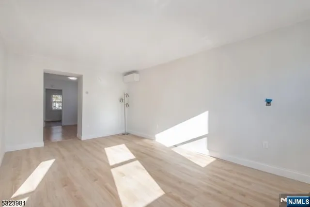 a view of a hallway with wooden floor and a refrigerator