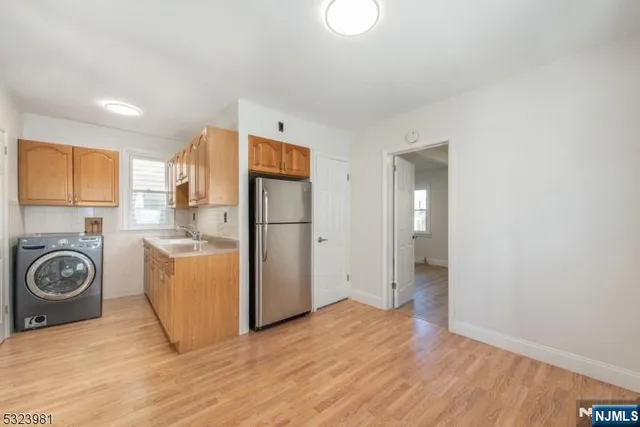 a view of a kitchen with refrigerator and wooden floor