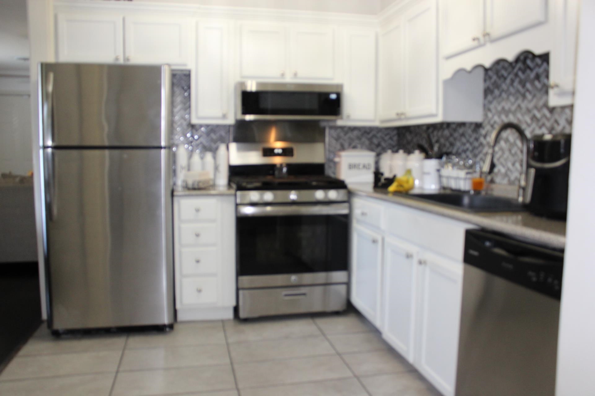 1534 Railton Road Memphis, TN 38111 - Photo 7 of 28 Kitchen featuring appliances with stainless steel finishes, light tile patterned floors, decorative backsplash, and white cabinetry