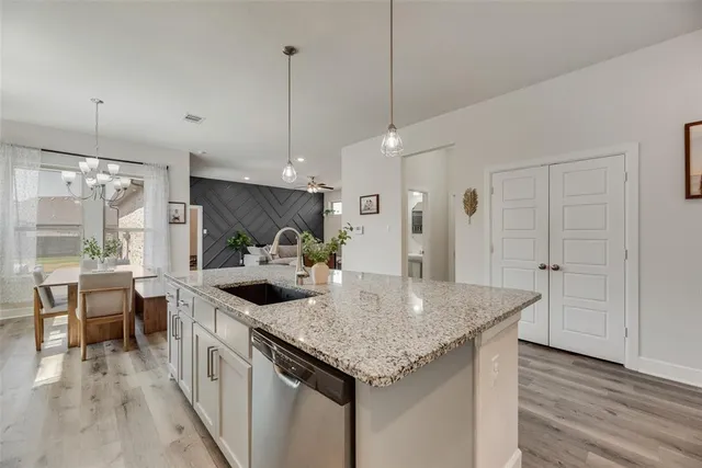 a kitchen with stainless steel appliances granite countertop a sink and a wooden floor