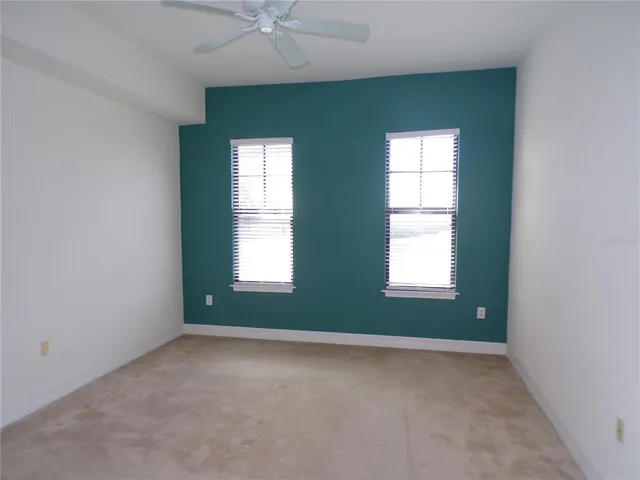 an empty room with a window and a fan
