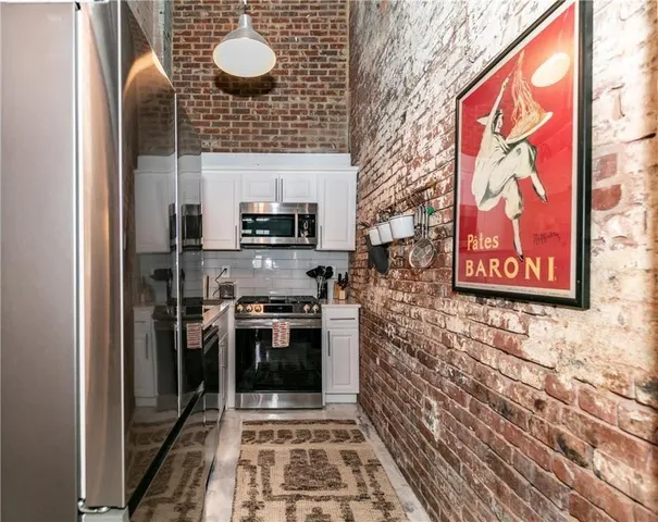a view of a refrigerator in kitchen and an empty room with wooden floor