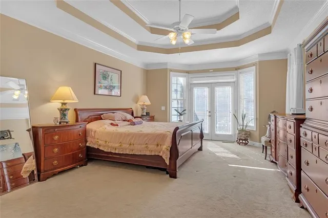 a spacious bedroom with a bed a chandelier and a dresser