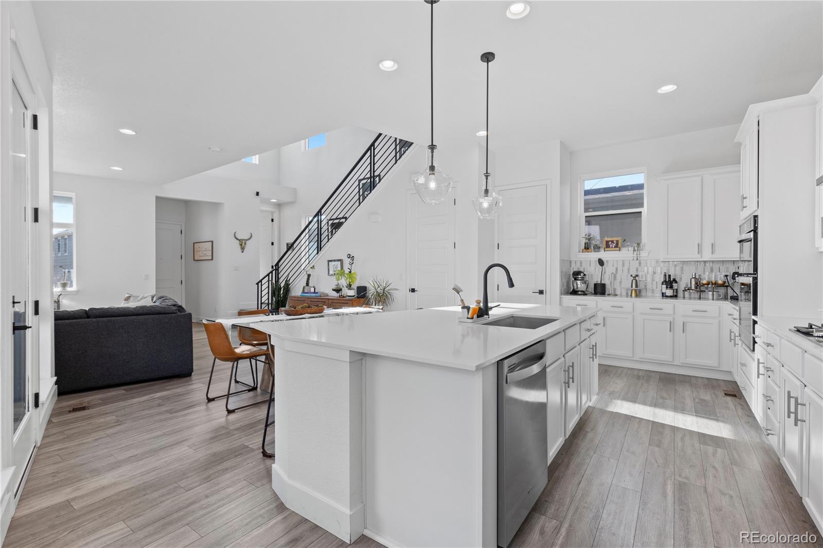 6058 North Perth Street Aurora, CO 80019 - Photo 18 of 47 a kitchen with a sink a counter top space stainless steel appliances and wooden floor