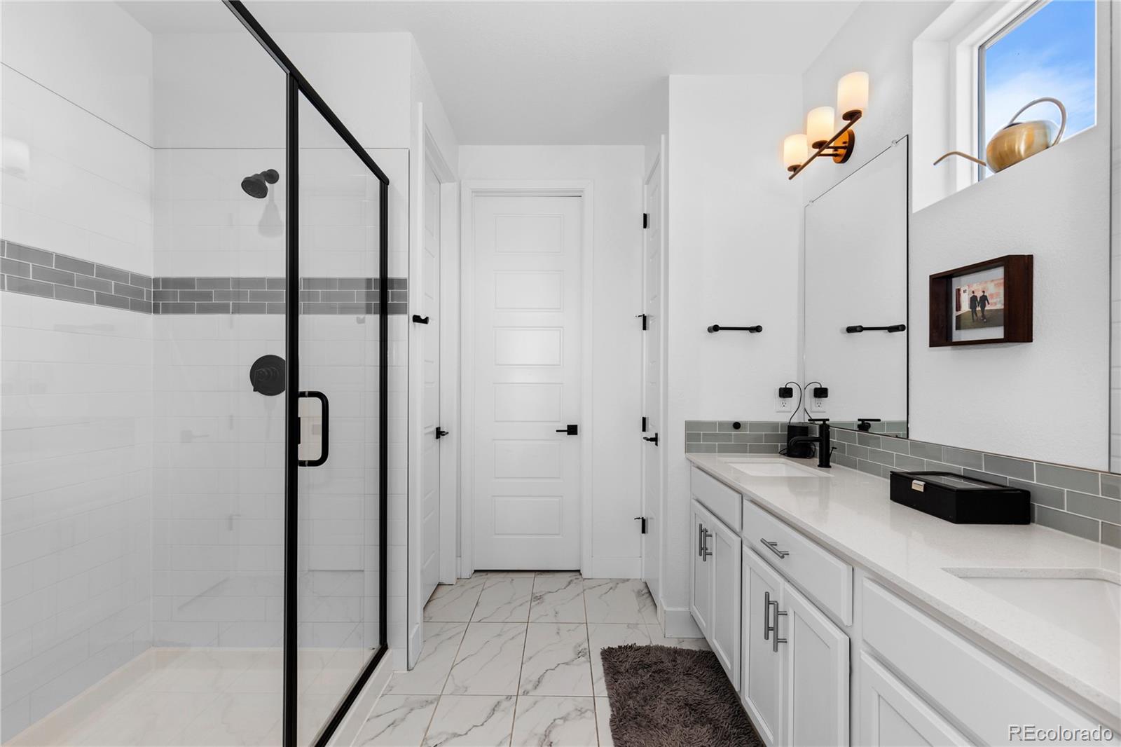 6058 North Perth Street Aurora, CO 80019 - Photo 33 of 47 a bathroom with a granite countertop sink a mirror a vanity and a shower