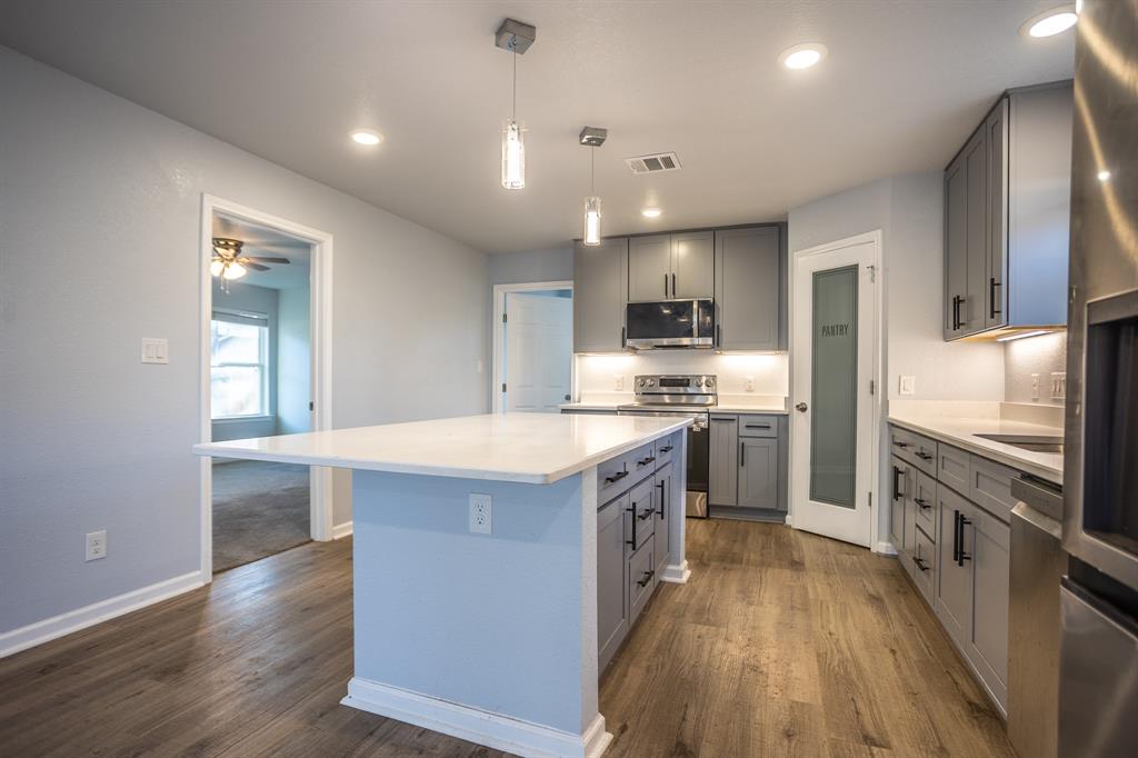 815 Ritchey Street Gainesville, TX 76240 - Photo 5 of 18 a kitchen with kitchen island granite countertop a sink stove and refrigerator