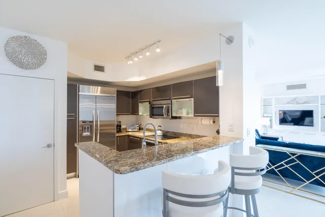 a kitchen with granite countertop kitchen island stainless steel appliances a sink and cabinets