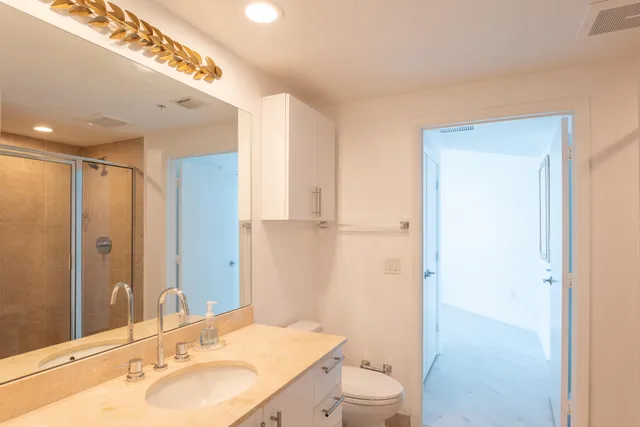 a bathroom with a granite countertop sink a toilet and shower