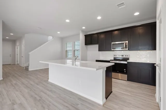 a large kitchen with stainless steel appliances kitchen island granite countertop a stove a sink and a microwave