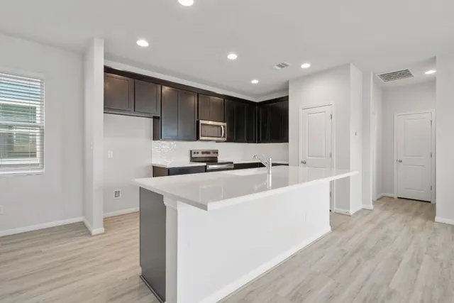 a large white kitchen with kitchen island a sink a center island stainless steel appliances and a window
