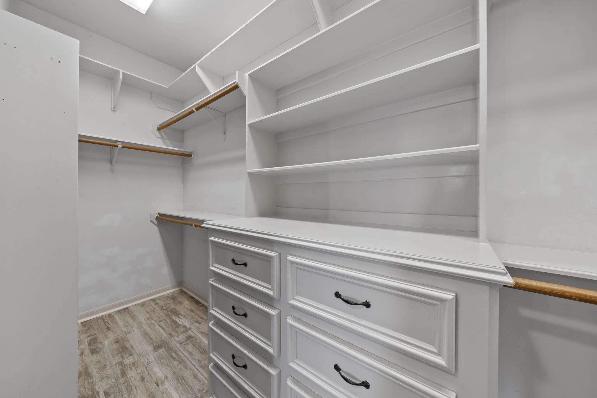 169 April Cove Montgomery, TX 77356 - Photo 16 of 39 Spacious walk-in closet in the primary suite featuring built-in shelving, multiple hanging areas, and a dresser with ample drawer storage. Thoughtfully designed for organization, this space offers plenty of room for wardrobe and accessories.