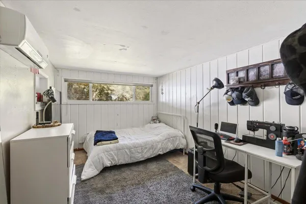 a bedroom with a bed a desk and chair with wooden floor