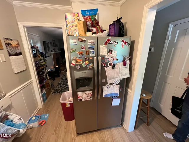a view of water heater room with fridge and wooden floor