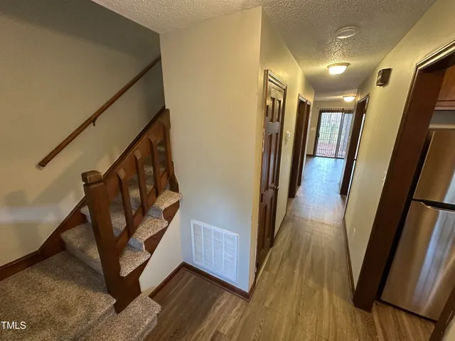 a view of a hallway with wooden floor and staircase