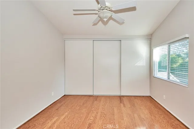 an empty room with wooden floor fan and windows