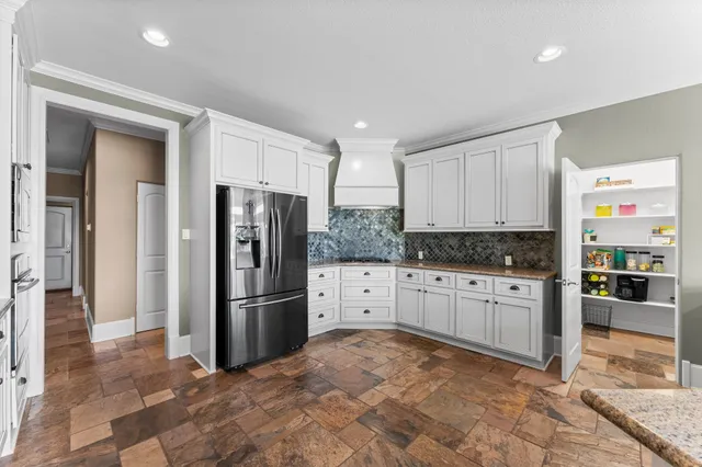 a kitchen with granite countertop a refrigerator and a stove top oven