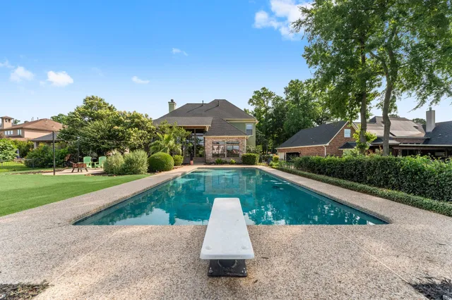 a view of a white house with a yard plants and large tree
