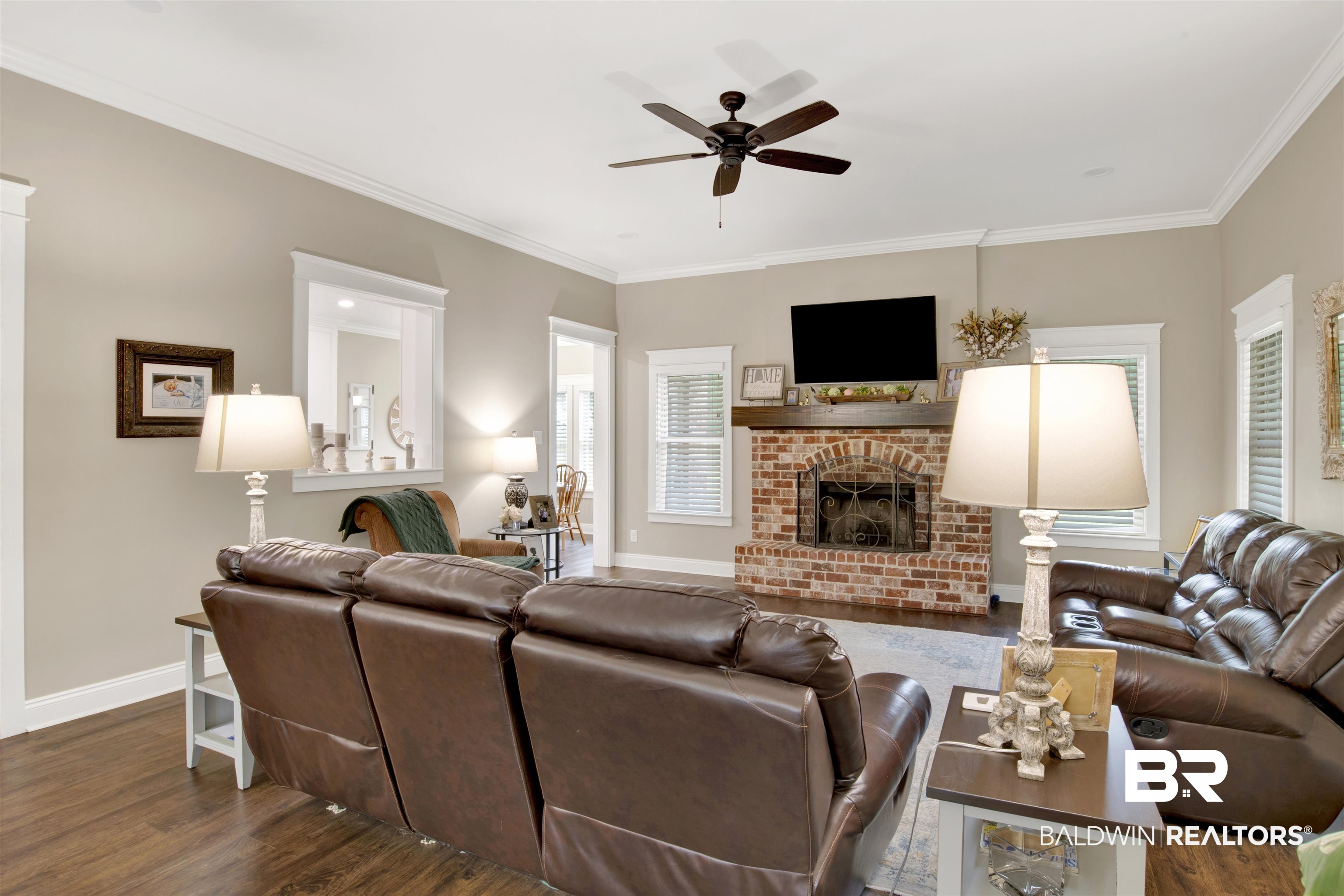 2440 Johnson Road West Mobile, AL 36695 - Photo 21 of 40 Living room featuring crown molding, ceiling fan, dark wood-type flooring, and a brick fireplace