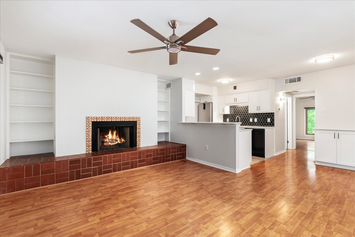 505 West 7th Street, Unit 313 Austin, TX 78701 - Photo 2 of 30 Unfurnished living room with a tile fireplace, light wood finished floors, visible vents, a ceiling fan, and built in shelves