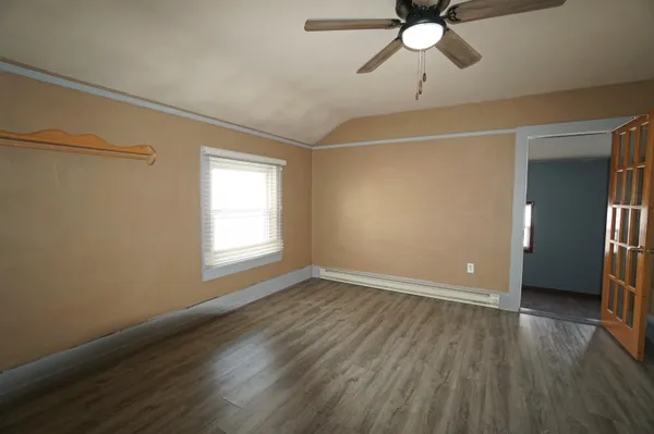 a view of an empty room with wooden floor and a window