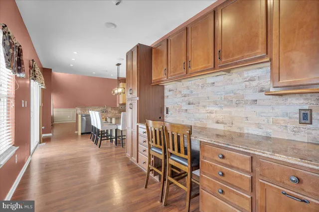 a kitchen with granite countertop a dining table chairs cabinets and stainless steel appliances
