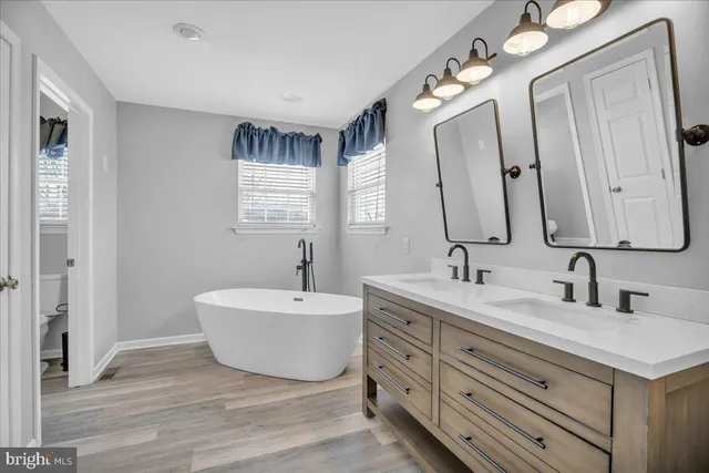 a spacious bathroom with a double vanity sink mirror and bathtub