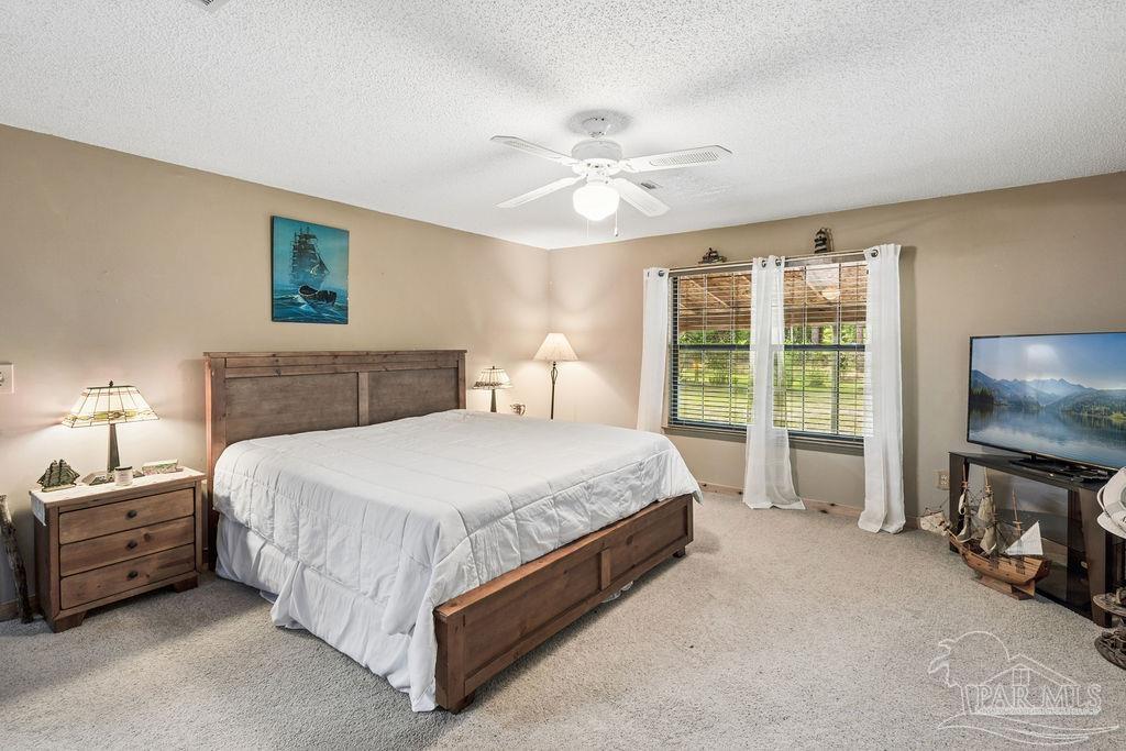 8938 Pioneer Road Holt, FL 32564 - Photo 18 of 44 a spacious bedroom with a bed and a flat screen tv