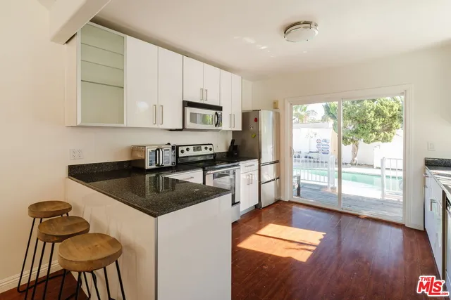 a kitchen with granite countertop a stove a sink a counter space and cabinets