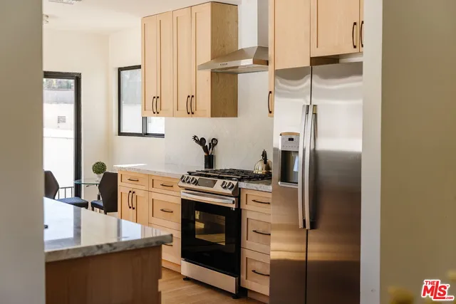 a kitchen with stainless steel appliances granite countertop a refrigerator a stove and a sink with large window