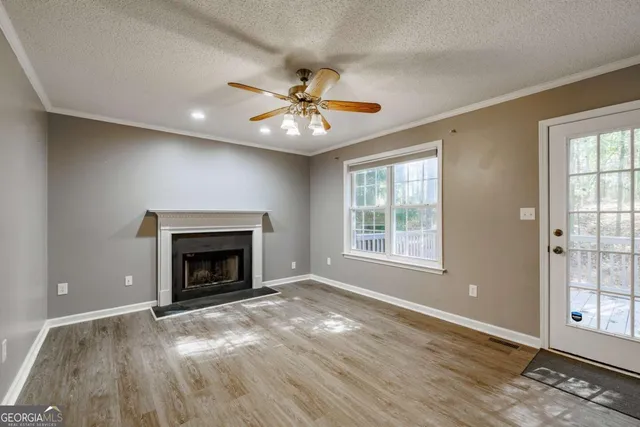 an empty room with windows fireplace and a kitchen view