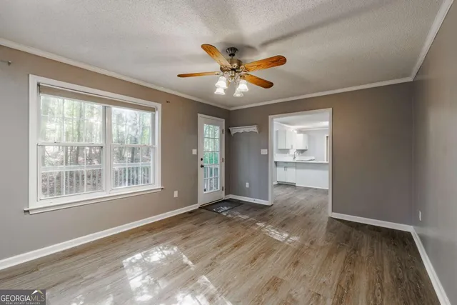 a view of an empty room with a window and wooden floor