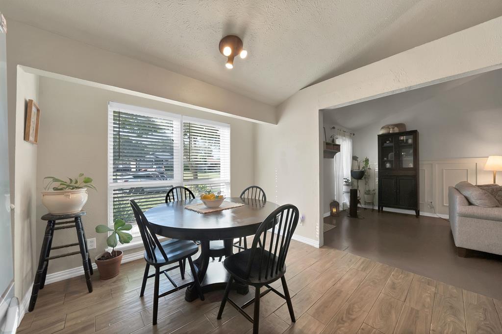 9519 County View Road Dallas, TX 75249 - Photo 11 of 31 Dining area featuring wood-finish flooring, a large window with white blinds, and a multi-bulb ceiling light fixture