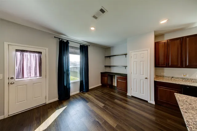 a living room with stainless steel appliances kitchen island granite countertop wooden floor a ceiling fan and a window