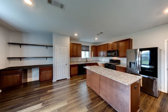 a kitchen with stainless steel appliances granite countertop a stove top oven a sink dishwasher a refrigerator and a oven with wooden floor