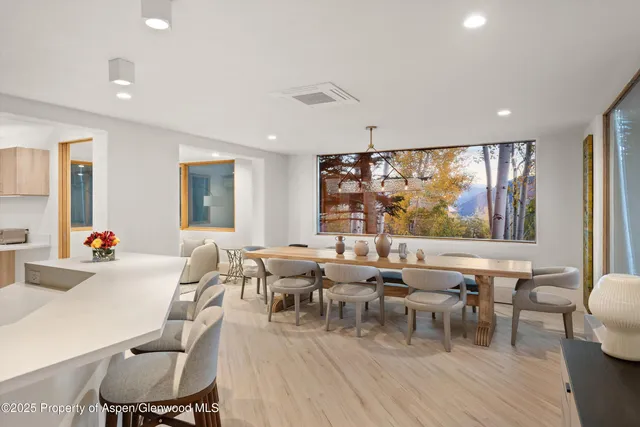 a room with lots of tables a large window and chairs