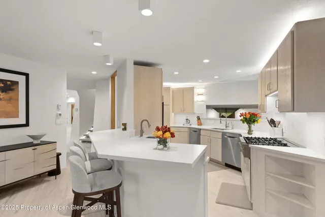 a large kitchen with stainless steel appliances a stove a sink a dining table and chairs
