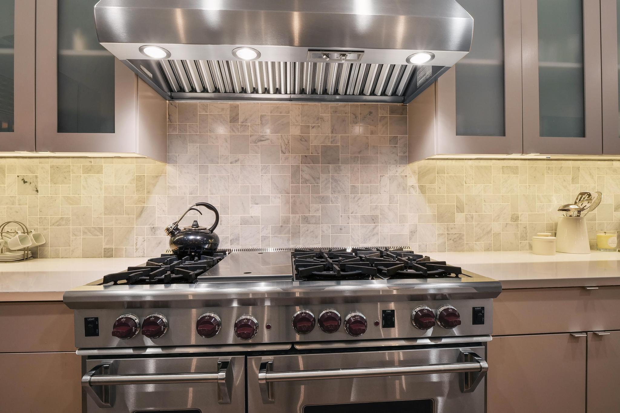 555 East 5th Street, Unit 3022 Austin, TX 78701 - Photo 14 of 40 Kitchen with glass insert cabinets, exhaust hood, range with two ovens, and backsplash