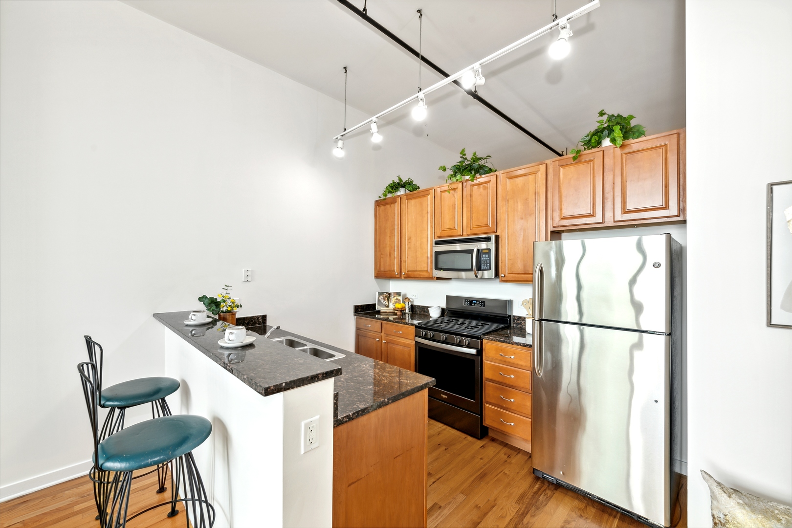 1224 West Van Buren Street, Unit 810 Chicago, IL 60607 - Photo 6 of 28 a kitchen with stainless steel appliances kitchen island granite countertop a refrigerator a stove a sink dishwasher and a dining table with wooden floor