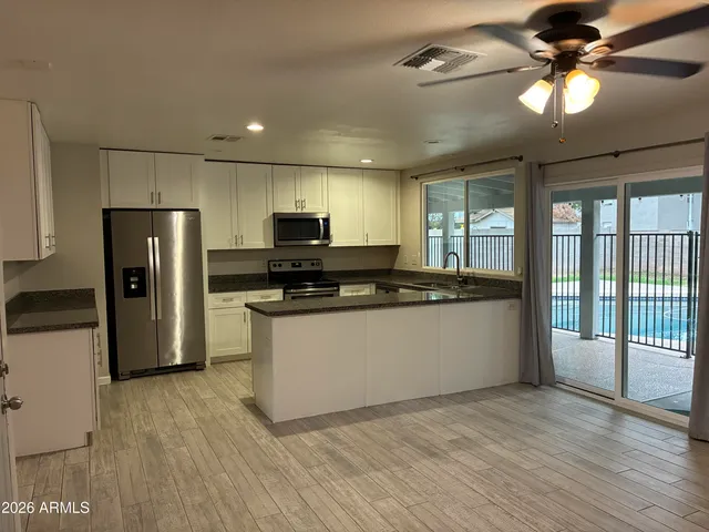 a kitchen with stainless steel appliances kitchen island granite countertop a stove a refrigerator a sink and a microwave