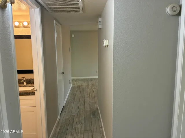 a view of a hallway with wooden floor and a bathroom