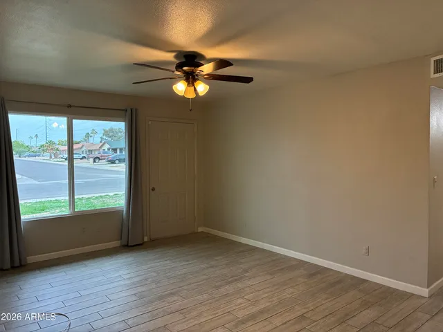 an empty room with wooden floor fan and windows