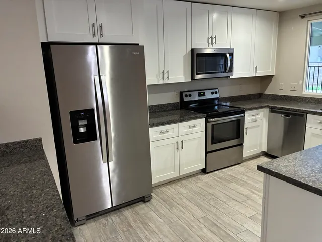 a kitchen with stainless steel appliances granite countertop a refrigerator stove a sink and dishwasher