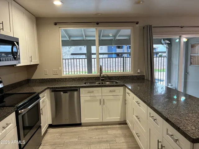 a kitchen with granite countertop a stove sink and cabinets