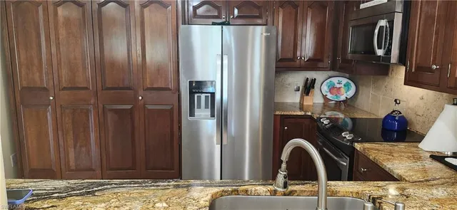 a bathroom with a granite countertop sink and a refrigerator