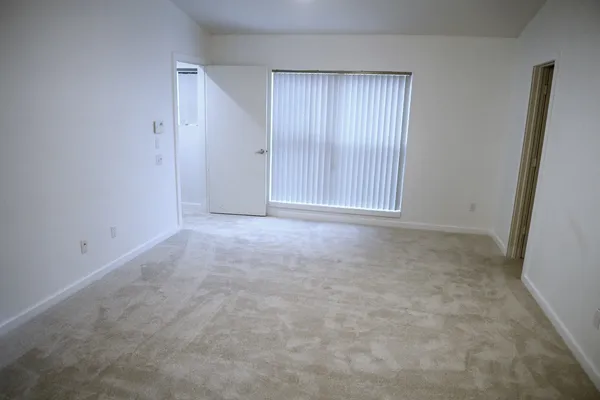 an empty room with wooden floor and fan
