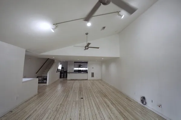 a view of empty room with wooden floor and fan