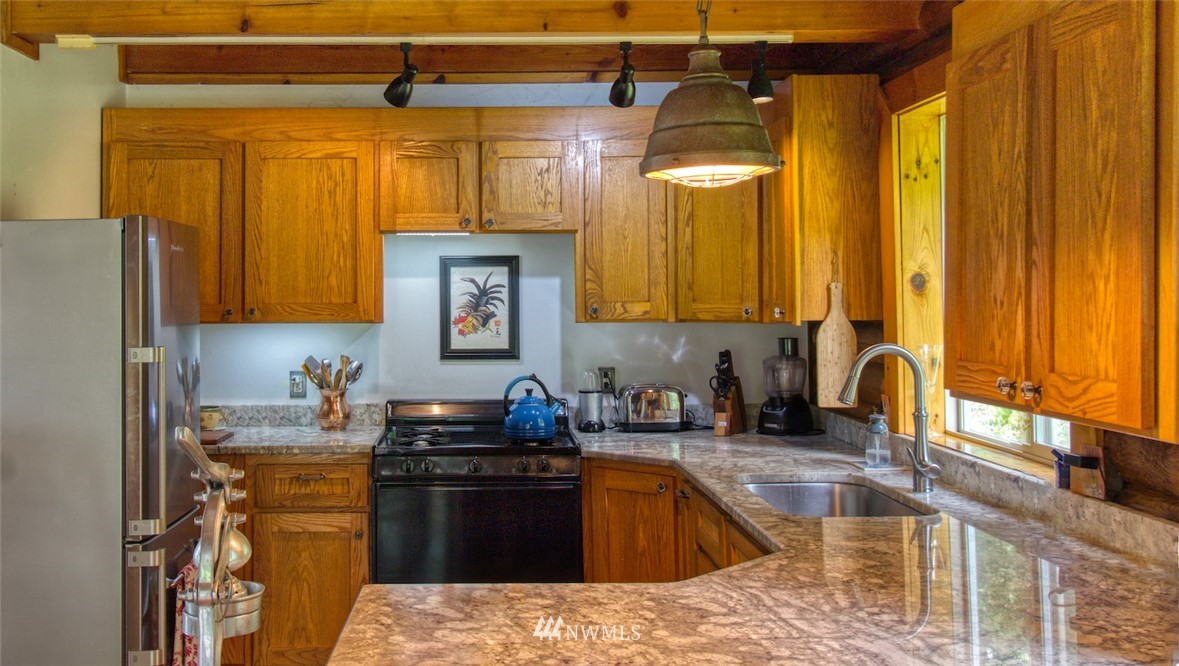 2707 Dabob Road Quilcene, WA 98376 - Photo 10 of 36 a kitchen with stainless steel appliances granite countertop a sink a stove and a wooden cabinets