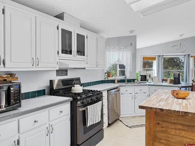 a kitchen with stainless steel appliances granite countertop a stove a sink and a white cabinets