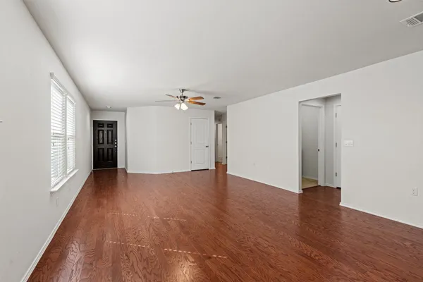 an empty room with wooden floor and windows